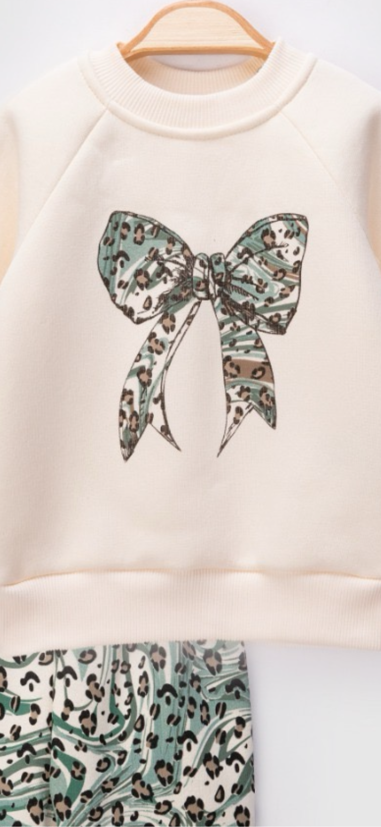 White sweatshirt with a large green leopard print bow design on a white background